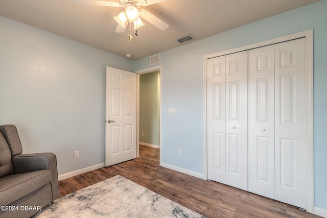 living area with ceiling fan, wood-type flooring, and a textured ceiling