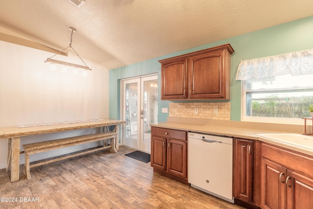 kitchen featuring light wood-type flooring, backsplash, a textured ceiling, sink, and dishwasher