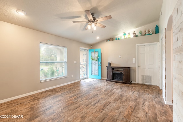 unfurnished living room with a textured ceiling, ceiling fan, vaulted ceiling, and hardwood / wood-style flooring