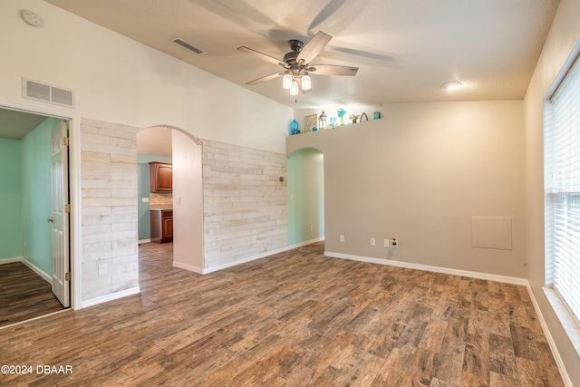 empty room featuring a textured ceiling, ceiling fan, dark wood-type flooring, and vaulted ceiling