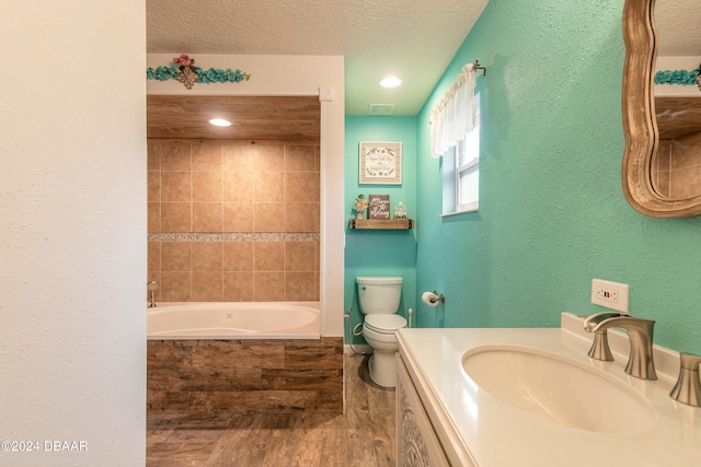 bathroom featuring a bathtub, vanity, toilet, a textured ceiling, and wood-type flooring