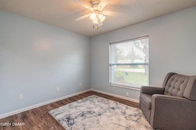 sitting room featuring hardwood / wood-style floors, ceiling fan, and a textured ceiling