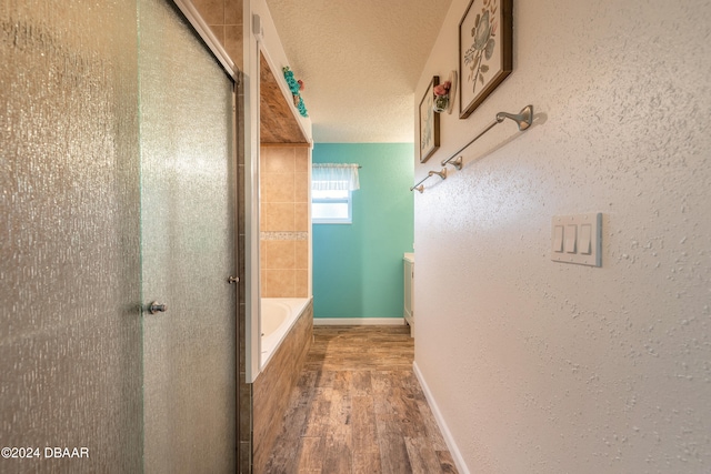 bathroom featuring wood-type flooring, a textured ceiling, and shower with separate bathtub