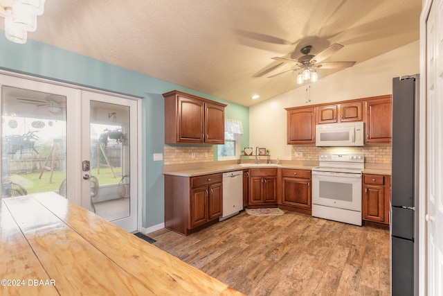 kitchen featuring decorative backsplash, a textured ceiling, white appliances, vaulted ceiling, and dark wood-type flooring