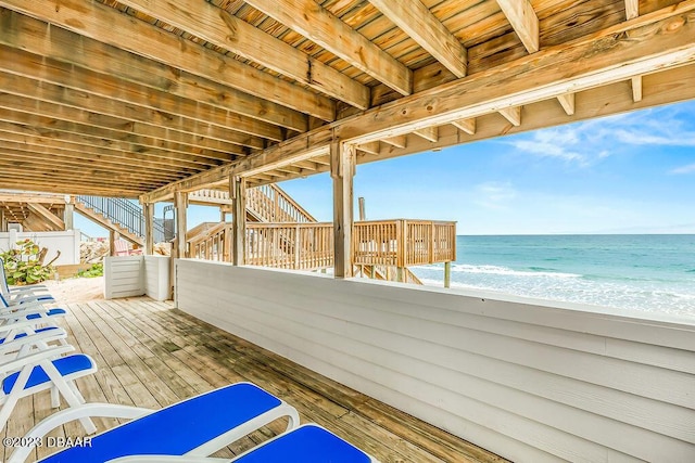 view of patio / terrace with a view of the beach, a deck with water view, and stairs