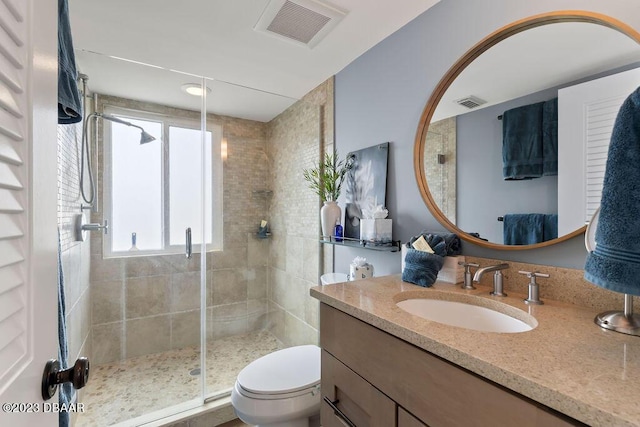 bathroom featuring a shower stall, toilet, vanity, and visible vents