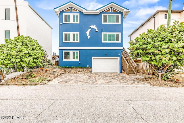 coastal inspired home featuring stairway, a garage, stucco siding, and driveway