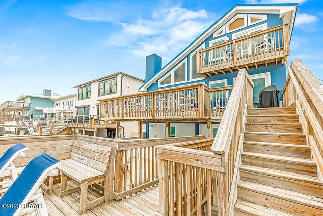 back of property with a balcony, a deck, and stairs