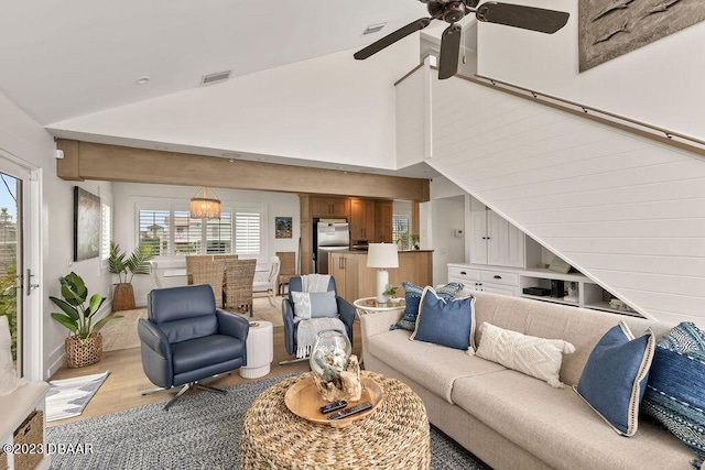 living area featuring ceiling fan, light wood-style flooring, visible vents, and high vaulted ceiling