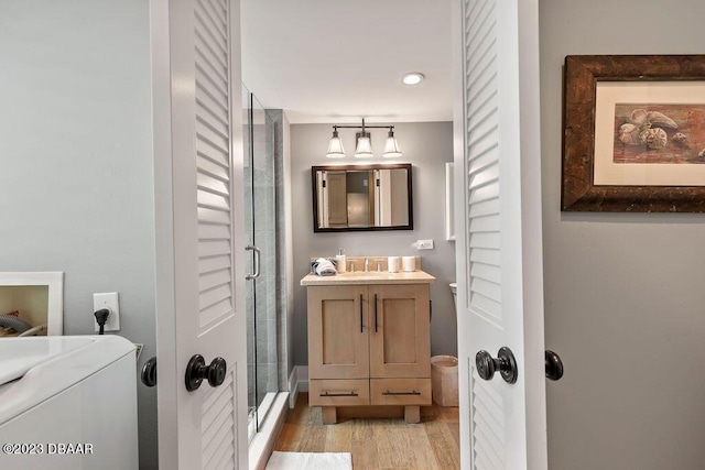 bathroom featuring wood finished floors, a shower stall, vanity, washer / clothes dryer, and recessed lighting