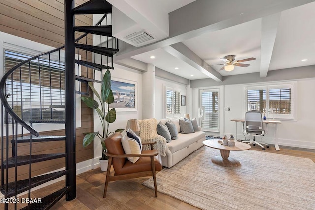 living area featuring a ceiling fan, baseboards, visible vents, stairway, and beam ceiling