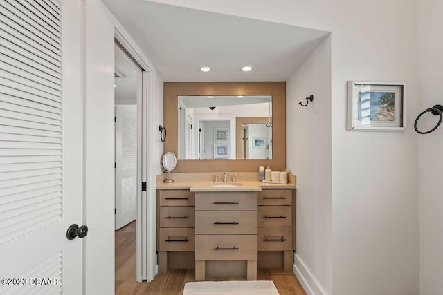 bathroom featuring baseboards, vanity, recessed lighting, and wood finished floors