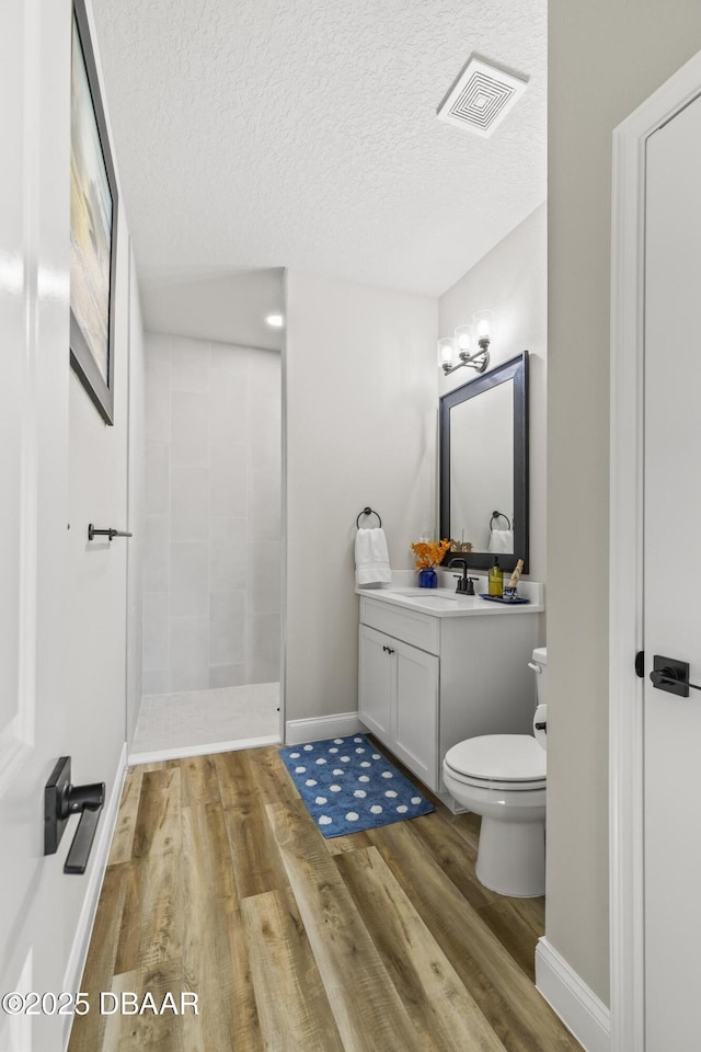 bathroom featuring hardwood / wood-style flooring, vanity, a textured ceiling, toilet, and walk in shower