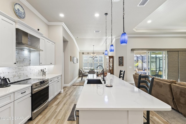 kitchen featuring a breakfast bar, decorative light fixtures, sink, stainless steel range with electric cooktop, and a center island with sink