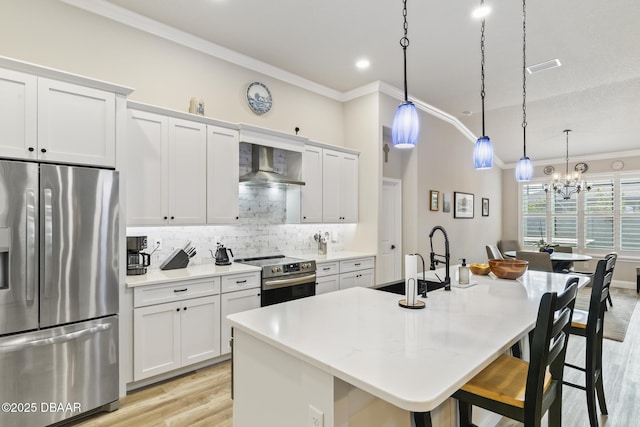 kitchen featuring appliances with stainless steel finishes, decorative light fixtures, white cabinetry, an island with sink, and wall chimney range hood