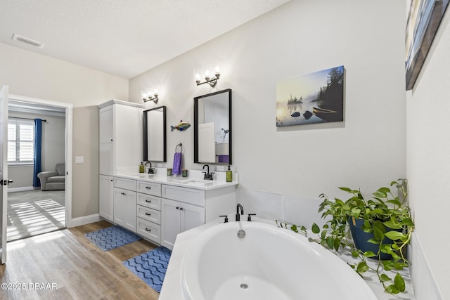 bathroom with vanity, hardwood / wood-style floors, and a tub to relax in