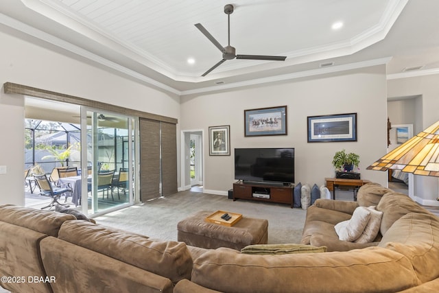 living room with crown molding, a raised ceiling, ceiling fan, and carpet