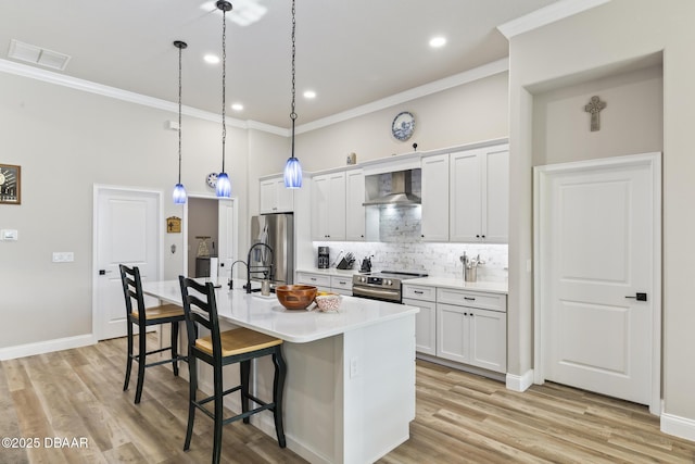 kitchen featuring a breakfast bar area, stainless steel appliances, white cabinets, a center island with sink, and wall chimney exhaust hood