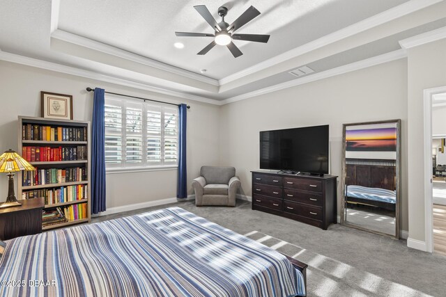 carpeted bedroom with ornamental molding and a raised ceiling