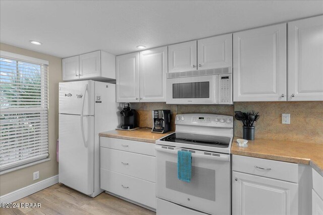 kitchen featuring white cabinetry, light wood-type flooring, decorative backsplash, and white appliances