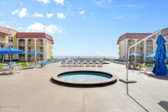 view of swimming pool with a community hot tub, a patio, and a water view