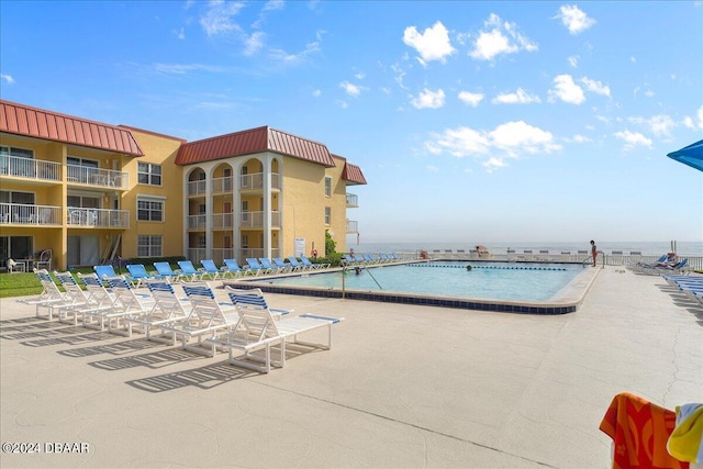 view of swimming pool featuring a patio and a water view