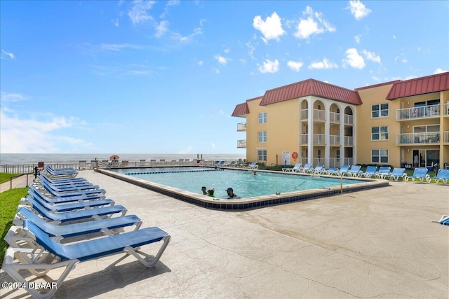 view of pool with a patio and a water view