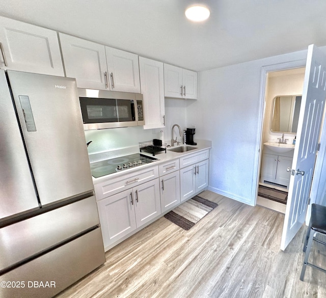 3112 S Atlantic Ave, Daytona Beach Shores, FL 32118 - kitchen with stainless steel appliances, a sink, light wood-style floors, white cabinets, and light countertops
