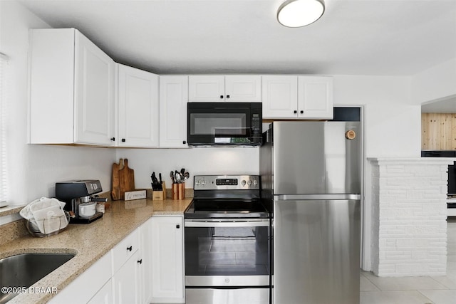 kitchen with light tile patterned flooring, light stone countertops, appliances with stainless steel finishes, and white cabinetry