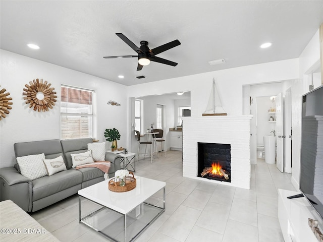 living room featuring a ceiling fan, recessed lighting, and a fireplace