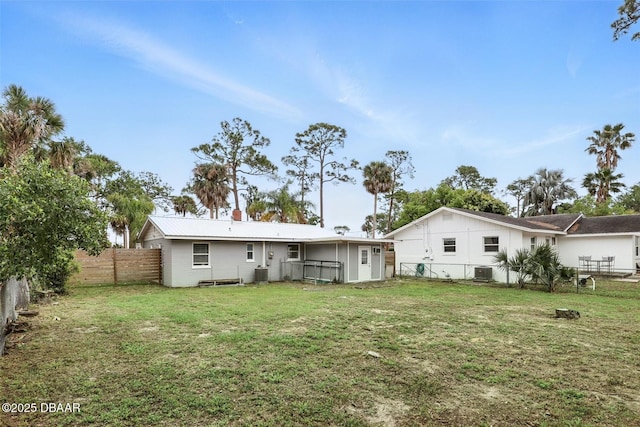 rear view of property featuring cooling unit, a yard, and fence