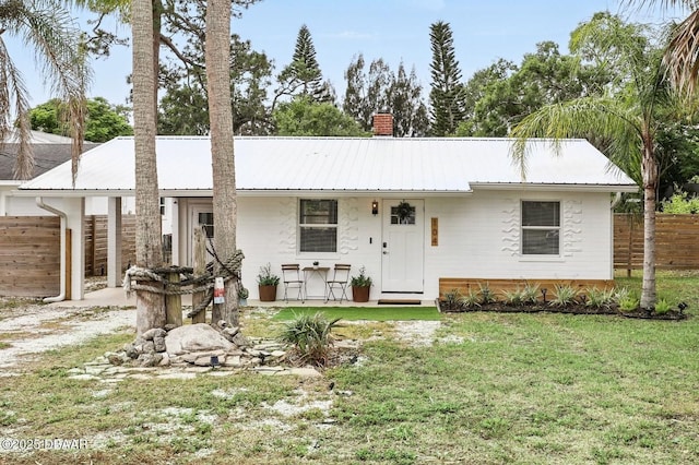 ranch-style house with fence, driveway, metal roof, and a front yard