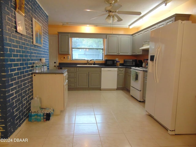 kitchen with white appliances, sink, ceiling fan, light tile patterned floors, and brick wall