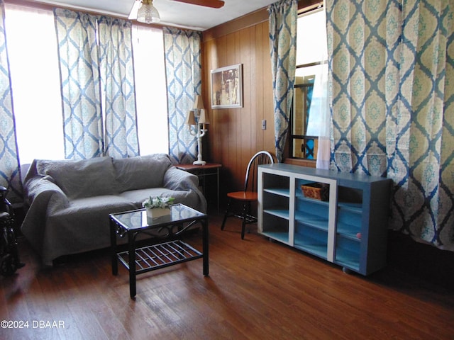 living room with hardwood / wood-style flooring, ceiling fan, and wood walls