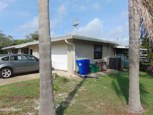 view of side of property with a lawn, cooling unit, and a garage