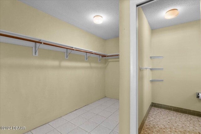 walk in closet with light tile patterned floors