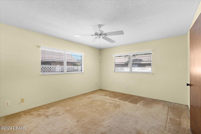 carpeted spare room featuring a textured ceiling and ceiling fan