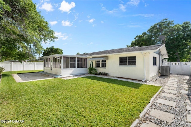 rear view of house featuring a patio, a sunroom, a lawn, and central air condition unit