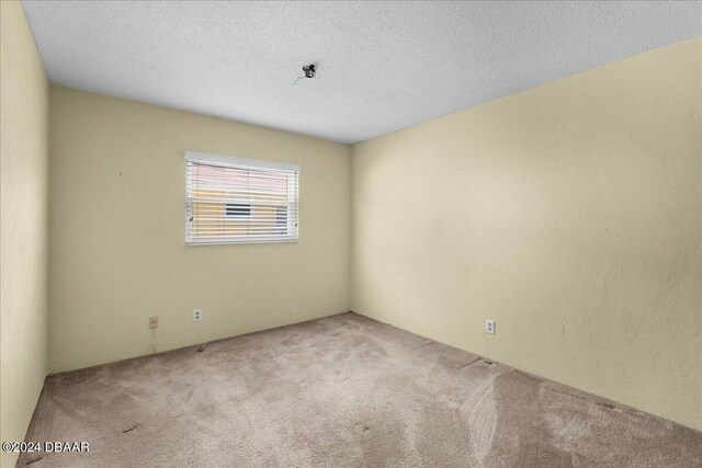 unfurnished room featuring carpet and a textured ceiling