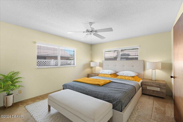 bedroom featuring ceiling fan, a textured ceiling, and light colored carpet