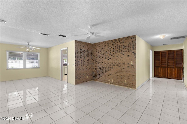 tiled spare room with tile walls, a textured ceiling, and ceiling fan