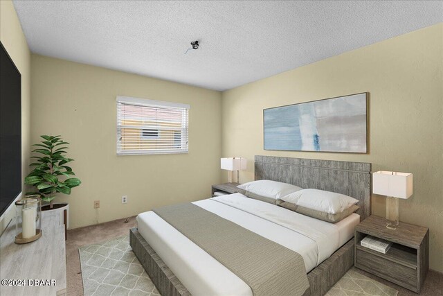 bedroom featuring a textured ceiling and light carpet