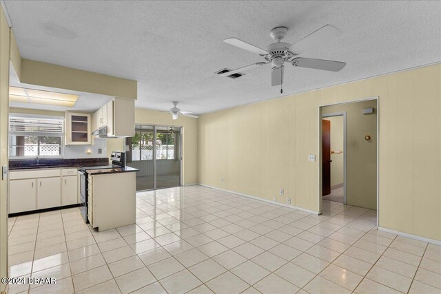 kitchen featuring white cabinets, range with electric stovetop, a healthy amount of sunlight, and light tile patterned flooring