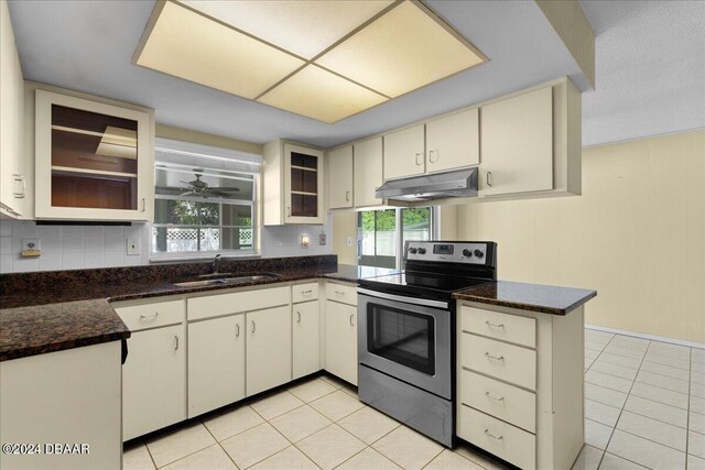 kitchen with stainless steel electric range, plenty of natural light, backsplash, and kitchen peninsula