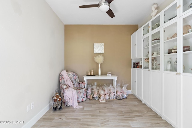 living area featuring light wood-type flooring and ceiling fan