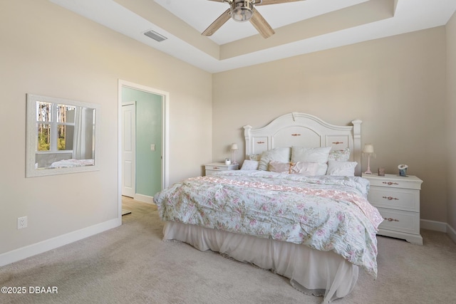 carpeted bedroom with ceiling fan and a tray ceiling