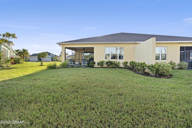 back of house featuring ceiling fan and a yard