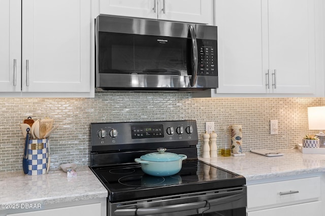 kitchen with backsplash, black / electric stove, and white cabinetry