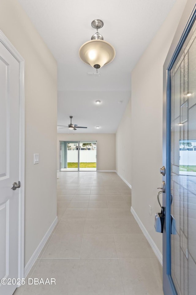 corridor featuring light tile patterned floors and baseboards