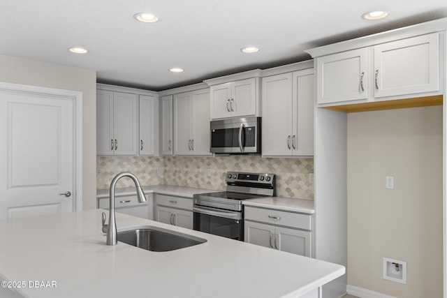 kitchen featuring recessed lighting, a sink, decorative backsplash, light countertops, and appliances with stainless steel finishes